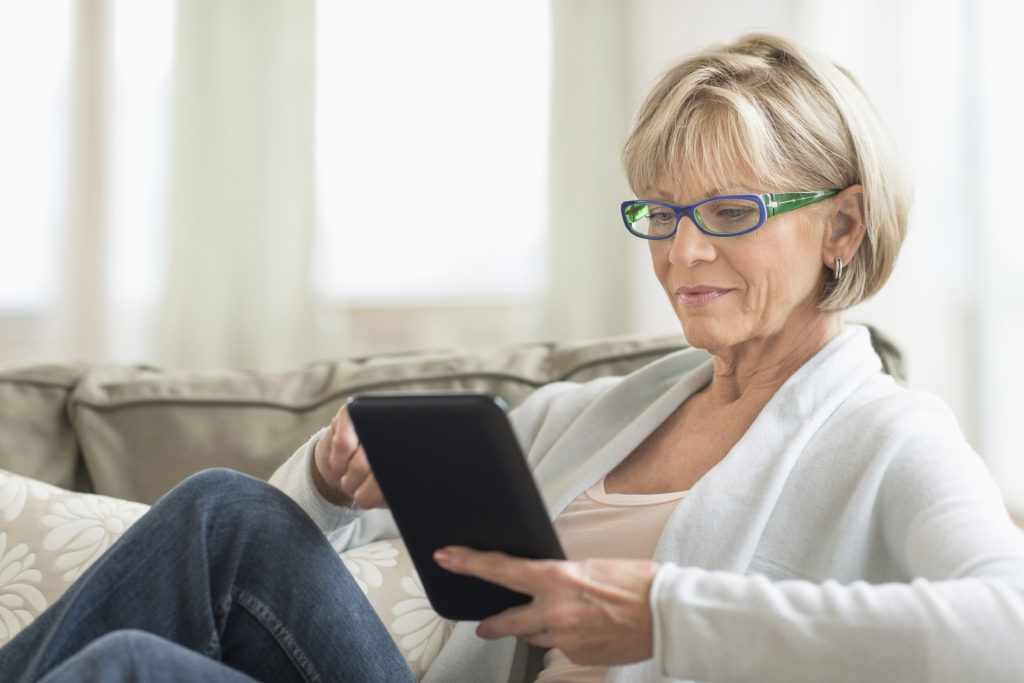 Mature woman using tablet computer looking for cost of moving house
